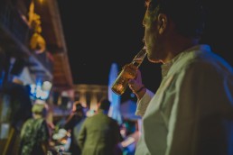 Gast trinkt locker sein gekühltes Bier auf einer Stadtstrandhochzeit unter freiem Himmel festgehalten von Hochzeitsfotografin Conny Schöffmann Photography, Würzburg