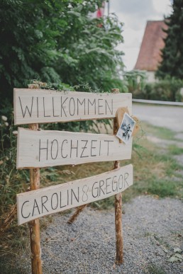 Natürliches Willkommensschild im Freien aus Holz fotografiert von Hochzeitsfotografin Conny Schöffmann Photography aus Würzburg