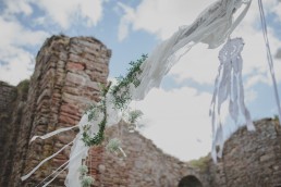 Stimmungsvoller Traubogen einer Ruinenhochzeit unter freiem Himmel fotografiert von Hochzeitsfotografin Conny Schöffmann Photography aus Würzburg