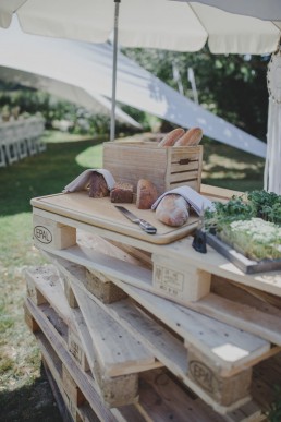 Leckere Snacks arrangiert auf natürlichen Holzpaletten auf einer Zelthochzeit unter freiem Himmel fotografiert von Würzburger Hochzeitsfotografin Conny Schöffmann Photography