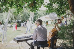 Entspannte Band spielt unter mit Traumfängern dekoriertem Baum Musik für die Gäste festgehalten von Hochzeitsfotografin Conny Schöffmann Photography aus Würzburg