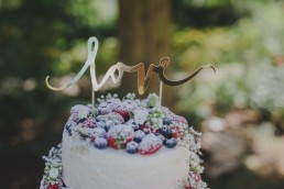 Goldener Love-Schriftzug auf der Hochzeitstorte einer Zelthochzeit im Freien festgehalten von Hochzeitsfotografin Conny Schöffmann Photography, Würzburg