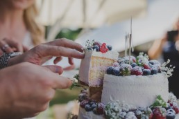 Bräutigam nimmt sich das erste Stück der natürlich dekorierten Hochzeitstorte einer Zelthochzeit in Würzburg fotografiert von Würzburger Hochzeitsfotografin Conny Schöffmann Photography