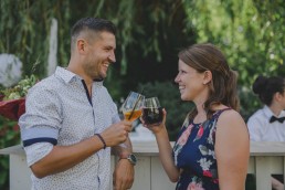 Lockeres Anstoßen zwischen zwei Gästen einer Zelthochzeit im Freien fotografiert von Würzburger Hochzeitsfotografin Conny Schöffmann Photography